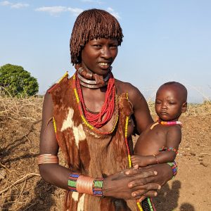 A Hamar tribe mother with traditional stranded hair tied with red clay and batter